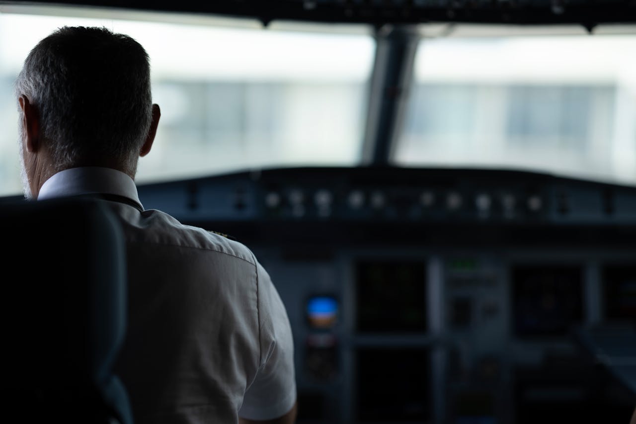 A focused view of an airline pilot in the cockpit, emphasizing responsibility and aviation control.