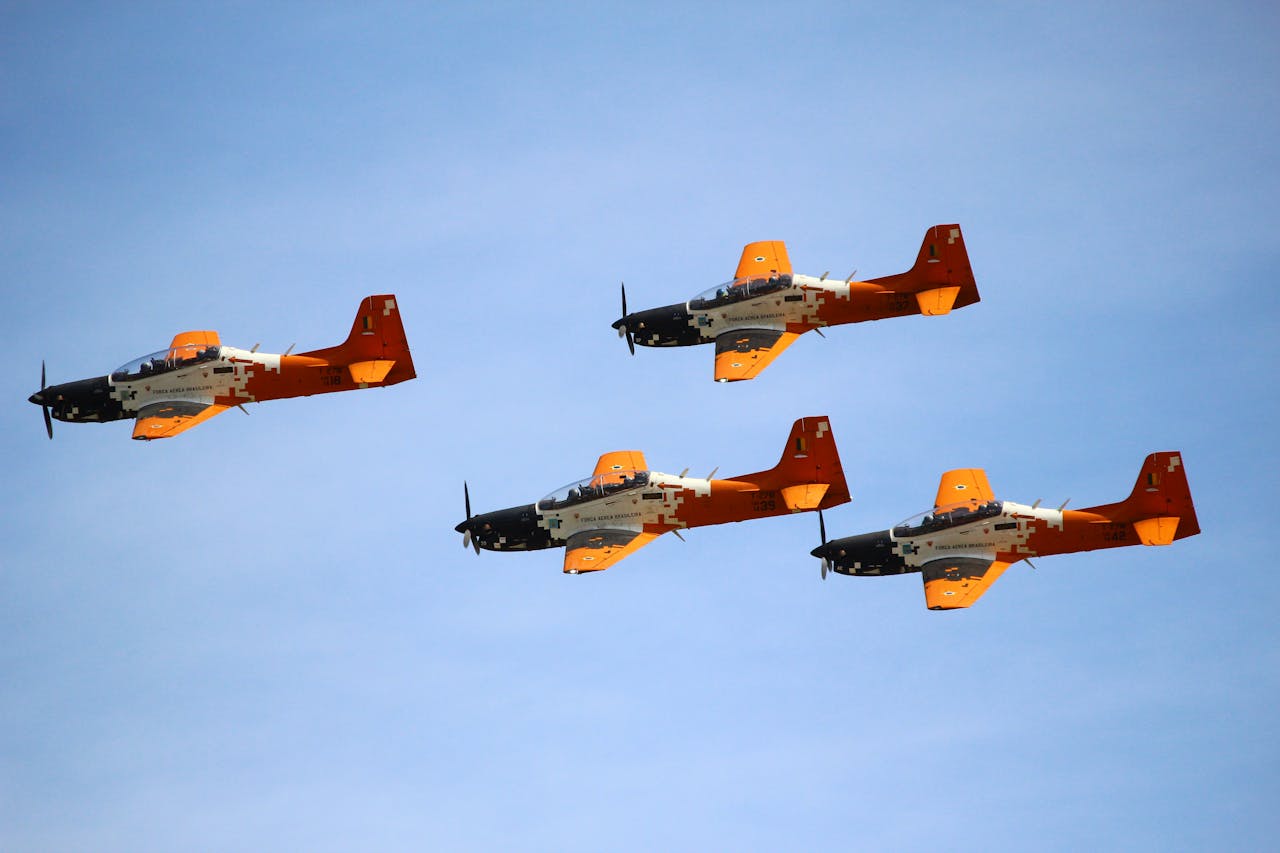 Four military airplanes in tight formation against a clear blue sky, showcasing precision aviation.
