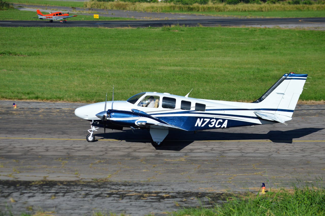 A small aircraft with registration N73CA taxiing on a sunny runway with green grass.